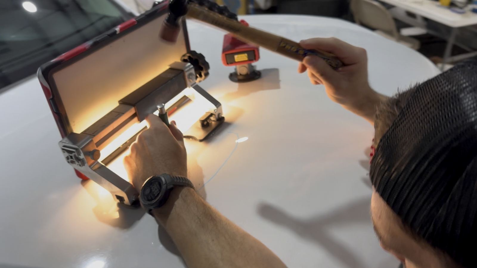 Technician using a PDR light board and tap-down tool on a car roof